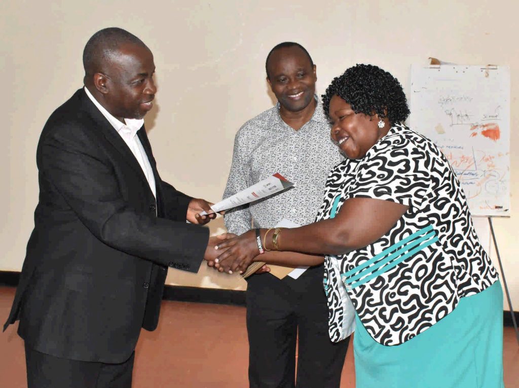  - Commissioner Dr. Patience Rwamigisha and Prof. Kaaya handover the certificate of attendance to one of the participants